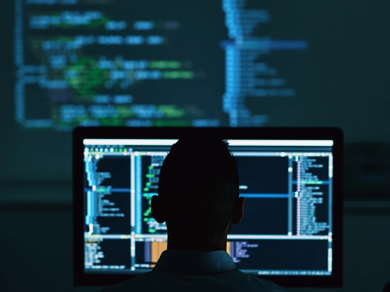 Developer at workstation with code on screens