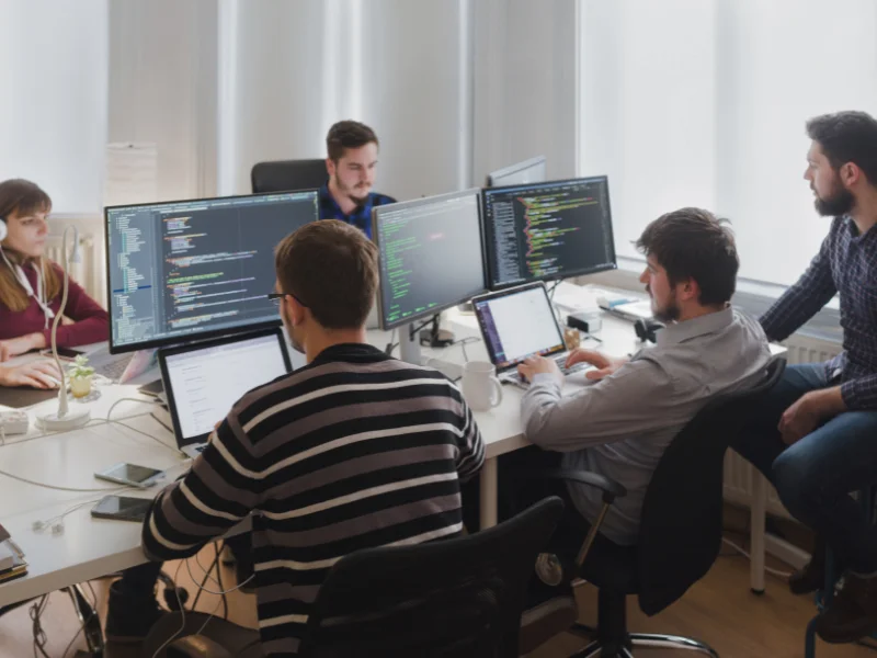 Team collaborating in front of multiple monitors